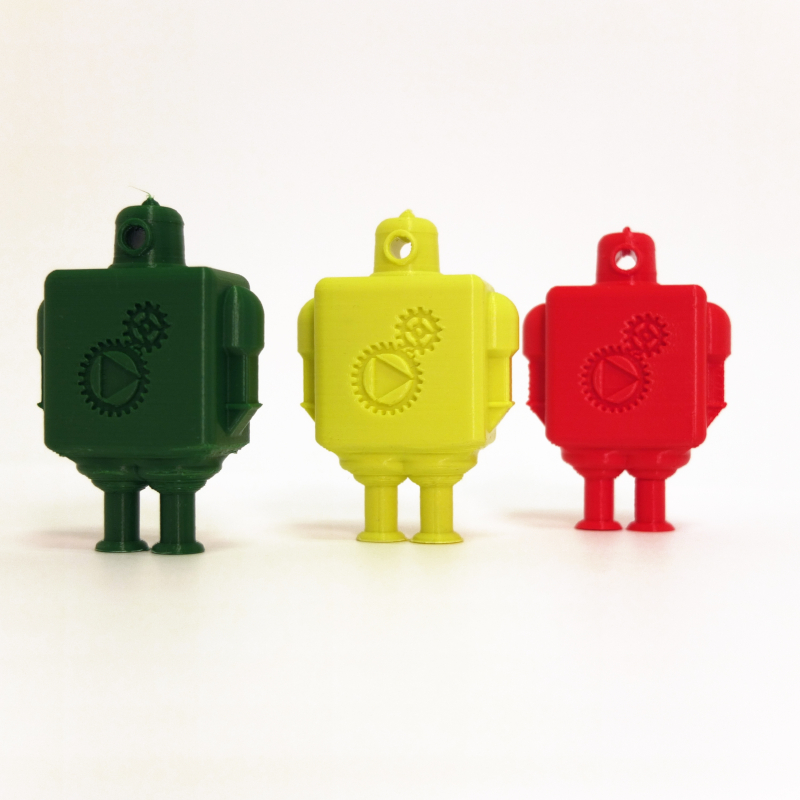 Three small 3D figurines, one green, one yellow and one red standing side by side