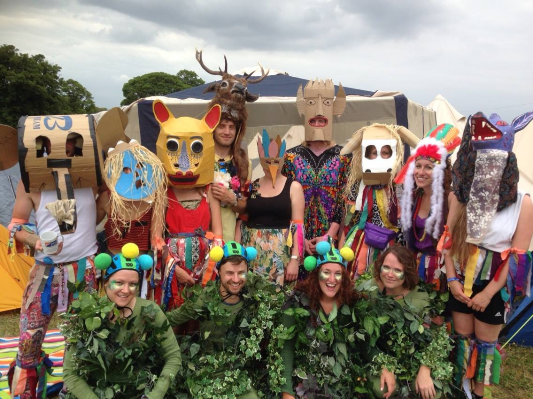 A group of people wearing colourful handmade masks and outfits standing outside together