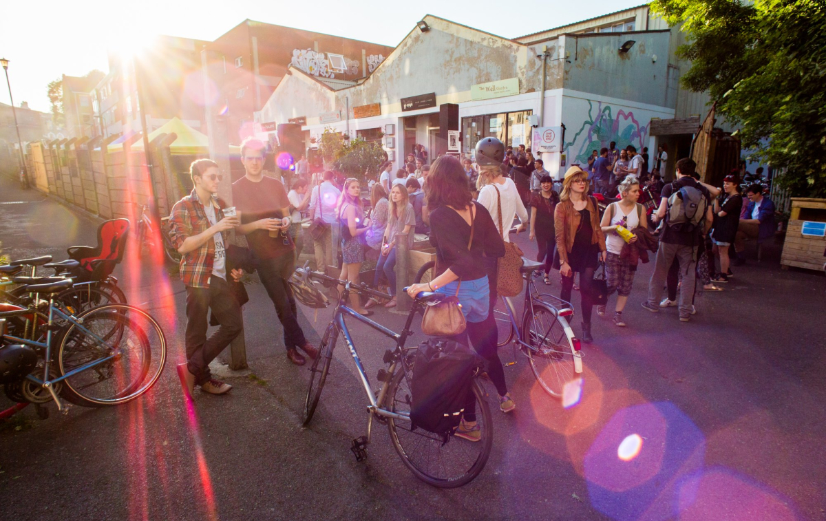 Sunset at Hackney Downs Studios. A crowd of people gather to drink and eat in the sunshine.