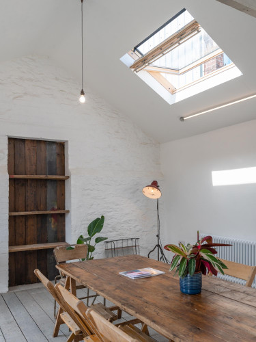 Skylit meeting room at Alma Yard featuring rustic wooden table, whitewashed walls, and natural light – ideal for team sessions and creative work.