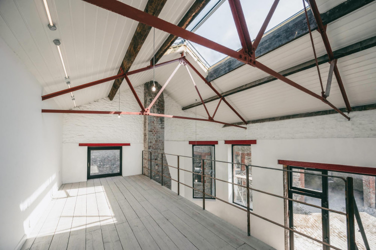 Bright, upper-level studio at Alma Yard with exposed red beams, large windows and original character features, ideal for creative businesses.