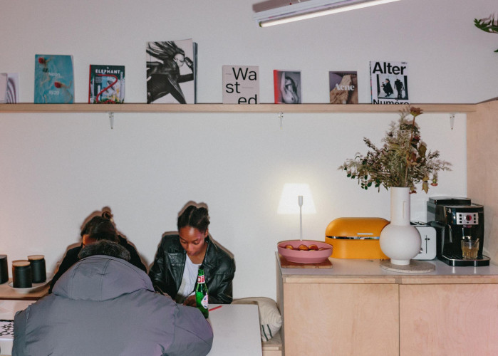 Creative residents socialising in the communal kitchen space with curated books and soft lighting