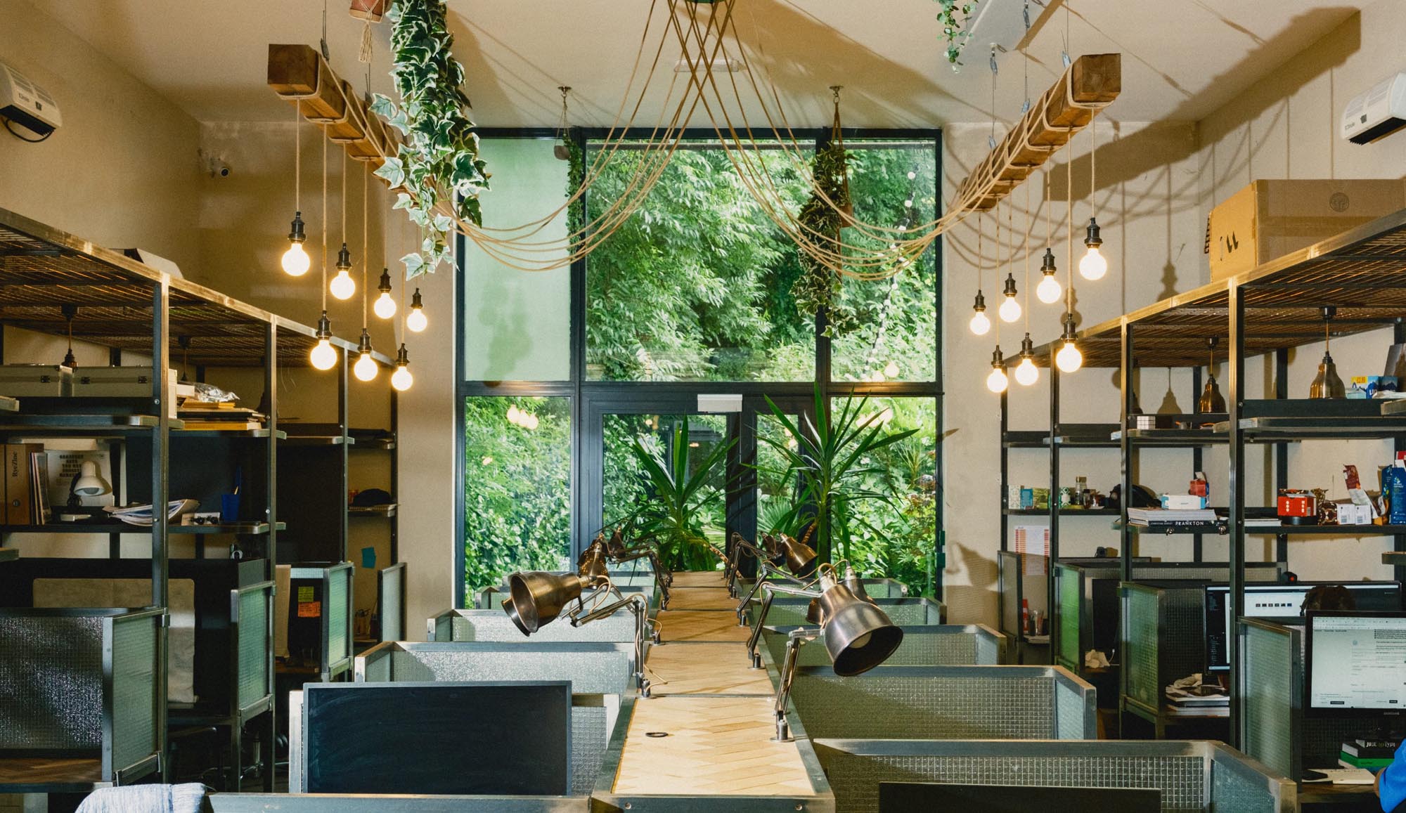 Creative coworking space at Hackney Downs Studios with leafy views, warm lighting and desk partitions