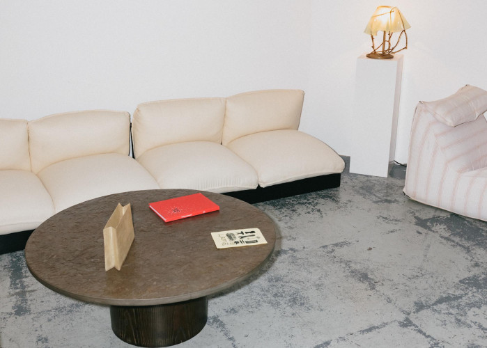 Minimalist lounge area with cream sofa, round coffee table and sculptural lamp inside Hackney Downs Studios