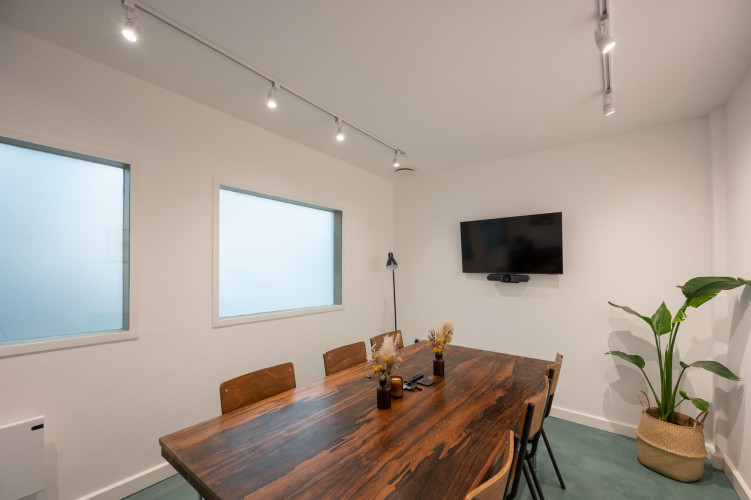 Contemporary meeting room at Hackney Downs Studios with natural wood table, screen setup and minimal decor
