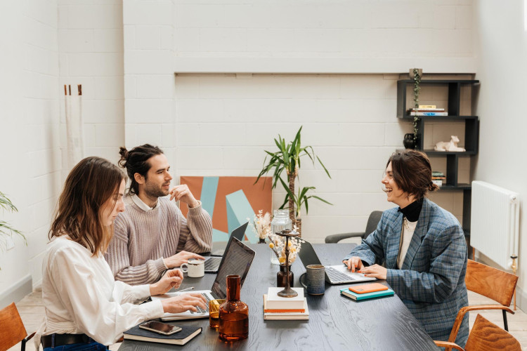 Group of residents collaborating at a communal desk in a bright, modern studio at Hackney Downs Studios
