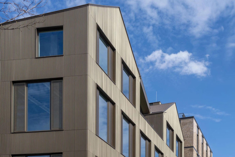 Architectural view of Lockside Studios in London, showcasing its corrugated metal facade and contemporary design against a blue sky