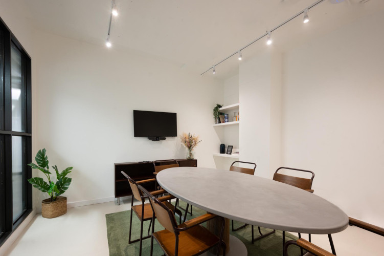 Contemporary meeting room at Netil Corner London with oval table, built-in screen, and industrial-modern details