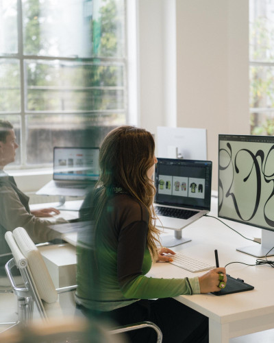Designers working at large monitors in a Netil House studio filled with natural light, reflecting collaborative creative workspaces
