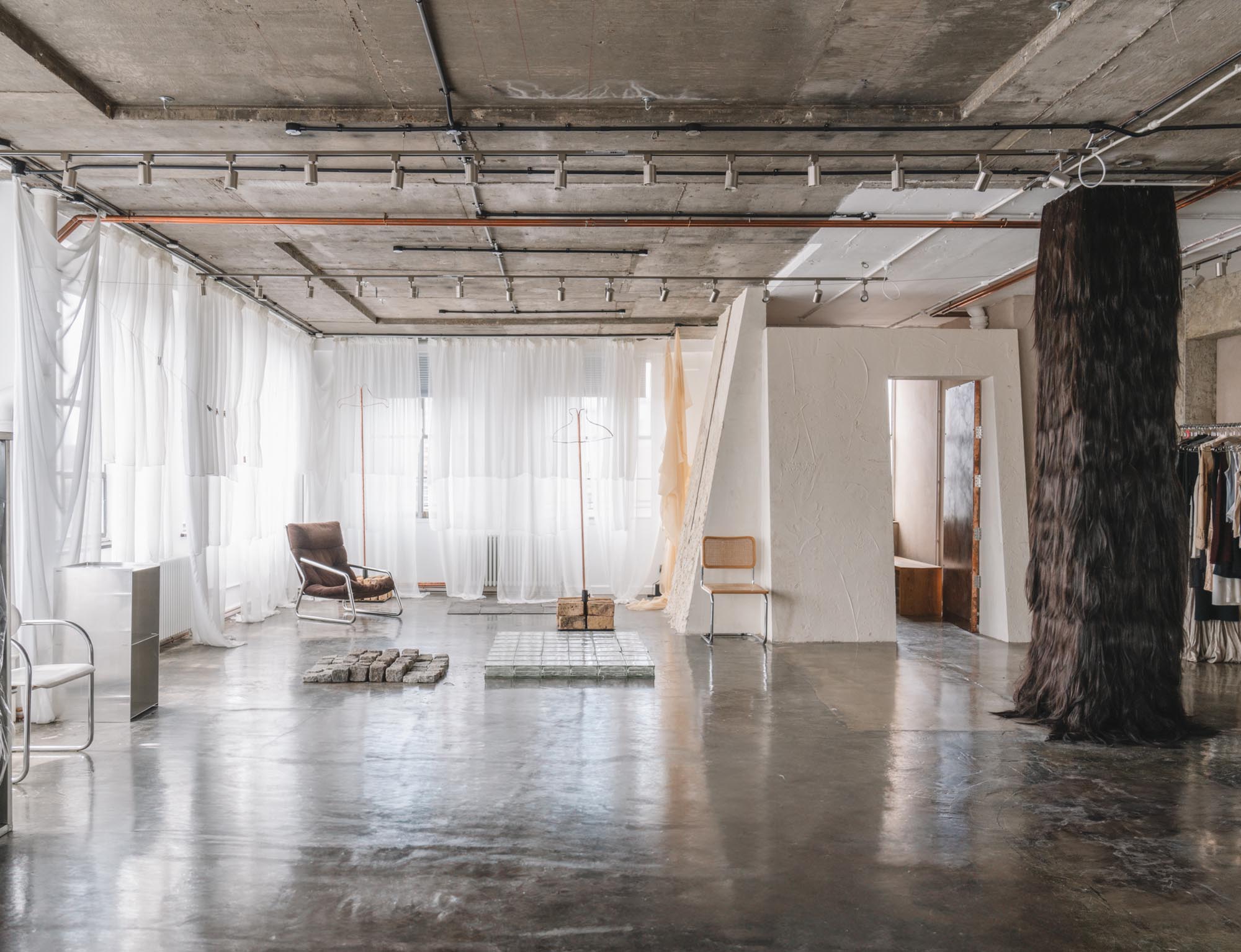Raw industrial studio at Netil House with polished concrete floors, textile installations and soft natural light through draped curtains