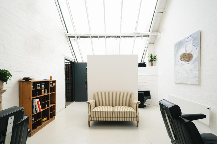Bright white-walled studio at Sunbury Workshops with striped sofa and skylight ceiling