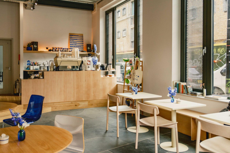 Design-led café inside Lockside Studios London, with pale wood furniture, modern decor and street-facing windows bringing in natural light