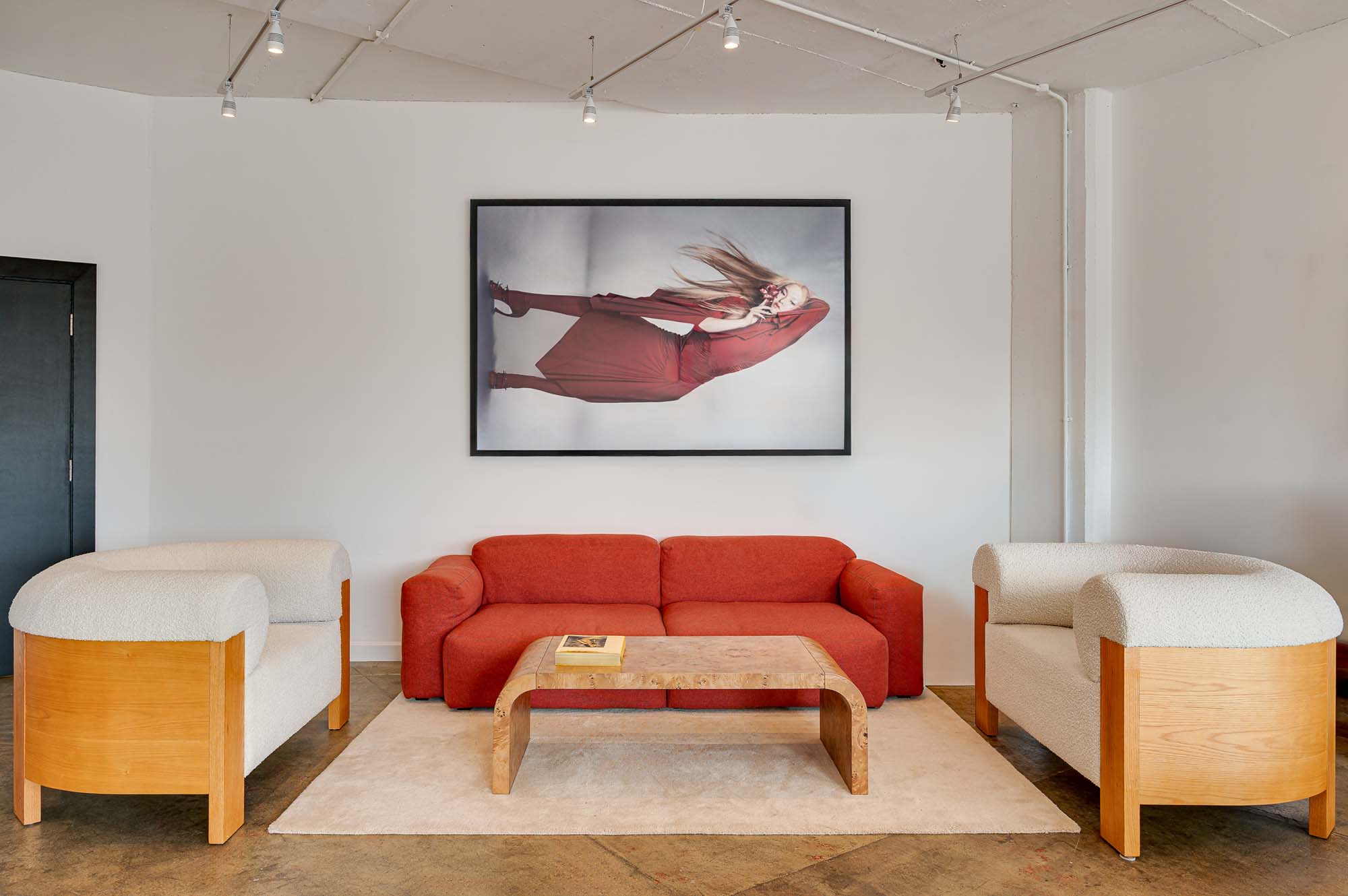 Creative studio interior with lounge seating, meeting table, framed artwork and industrial-style lighting.